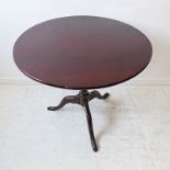 A George III period circular tilt-top mahogany occasional table: turned stem and on tripod base with