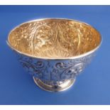 A hallmarked silver sugar bowl: gilded interior and decorated in repoussé style with flowerheads,