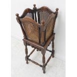 An early 20th century oak and rattan cane-sided plant stand on base with turned legs and carved