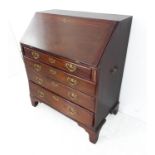 An 18th century mahogany writing bureau: the angular cleated fall opening to reveal fully-fitted