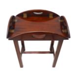A small oval folding mahogany butler's tray on stand (as a table) with brass hinges and folding