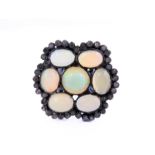 An unusual black lacquered silver ring set with seven opals surrounded by small diamonds, ring