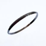 A silver bangle engraved with a double band of horizontal lozenges