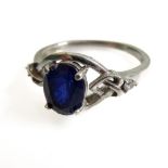 A silver dress ring set with an oval vertically aligned dark-blue stone within an openwork Celtic