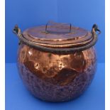 A large and heavy battered copper cauldron-style cooking pot with wrought-iron swing-handle (approx.