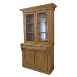 A late 19th century pine bookcase: the flaring corners above two glazed doors enclosing shelves