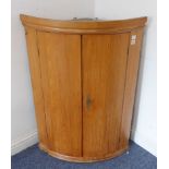 A late 18th century bow-fronted hanging pine corner cupboard (72cm wide)