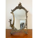 A gilt framed easel-style looking glass in high Rococo style with a seated cherub to the left (