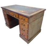 An early 20th century walnut pedestal desk: the leather inset top with gadrooned moulding an
