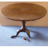 A 19th century circular oak tilt-top occasional table with turned stem and tripod base (81 cm in