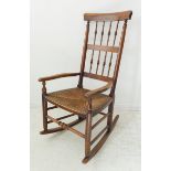 A late 19th century fruitwood rocking chair with turned spindles, rush seat and high turned