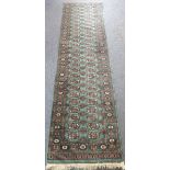 A hand-knotted Pakistan Belouch runner: the turquoise ground with a myriad of gul designs (298 cm