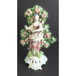 An early 19th century hand-decorated female bocage figure: she holds flowers above a floral wreath