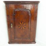 A George II period mid-18th century and feather-banded wall-hanging corner cupboard: the shaped