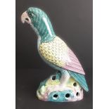 A Kangxi-style porcelain parrot decorated in greens, yellows and blues upon a reticulated rockwork