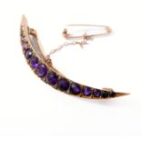 A late 19th/early 20th century amethyst and half pearl crescent brooch: the graduated line of