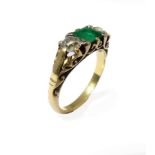 An emerald and diamond-set ring: the central rectangular step-cut emerald set to either side by an