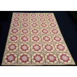 A good hand-stitched tapestry rug: beige ground with a 35-roundel symmetrical design of red, blue