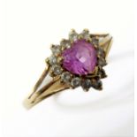 A 9-carat yellow gold ring centrally set with a pink cut stone surrounded by further, smaller