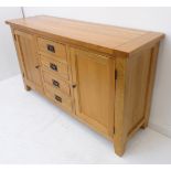 A quality modern solid oak sideboard: four central drawers flanked by two cupboard doors enclosing