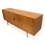 A fine mid-20th century teak sideboard of rectilinear shape: two tambour-style doors sliding to