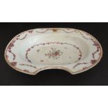 An 18th century Chinese porcelain barber's bowl of oval form and decorated with swags and floral