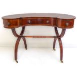 An early 20th century kidney-shaped mahogany cross-banded and boxwood-strung desk: the central