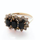 A 9-carat gold ring set with three black stones surrounded by white stones, ring size J/K  (boxed)