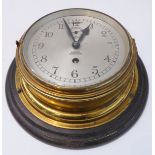 A brass-cased ship's clock; the dial marked 'Barkers - Kensington' (wooden mount 28 cm in diameter)
