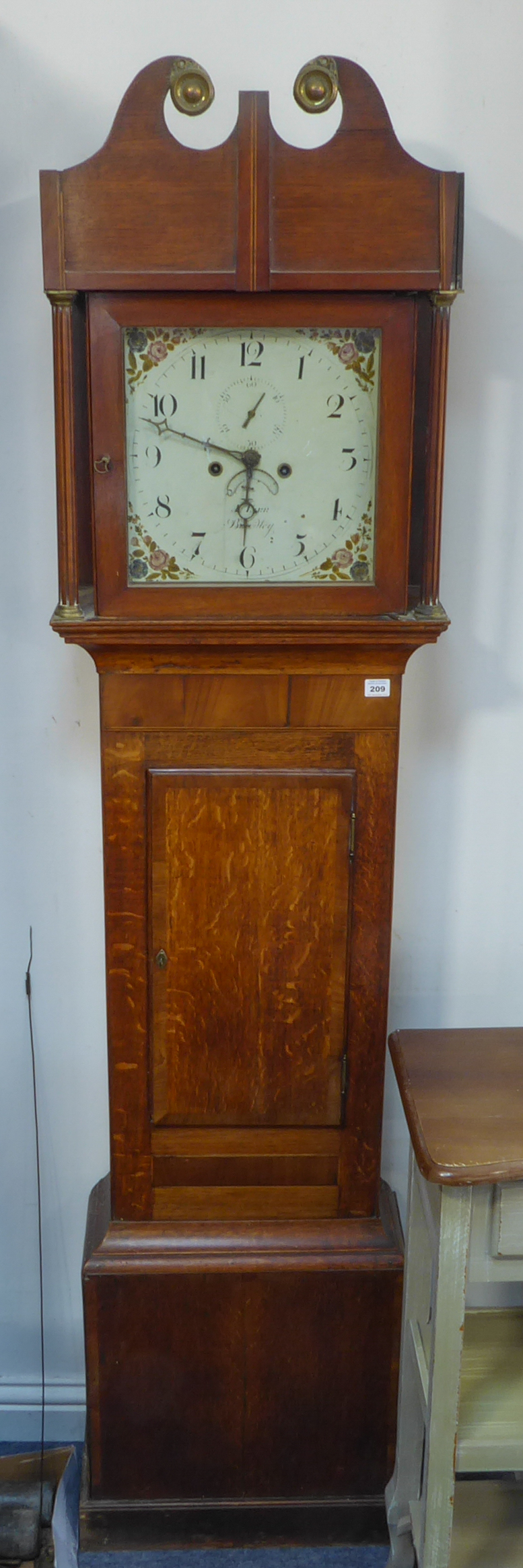 A 19th century thirty-hour oak longcase clock: the broken swan-neck pediment above a glazed hood