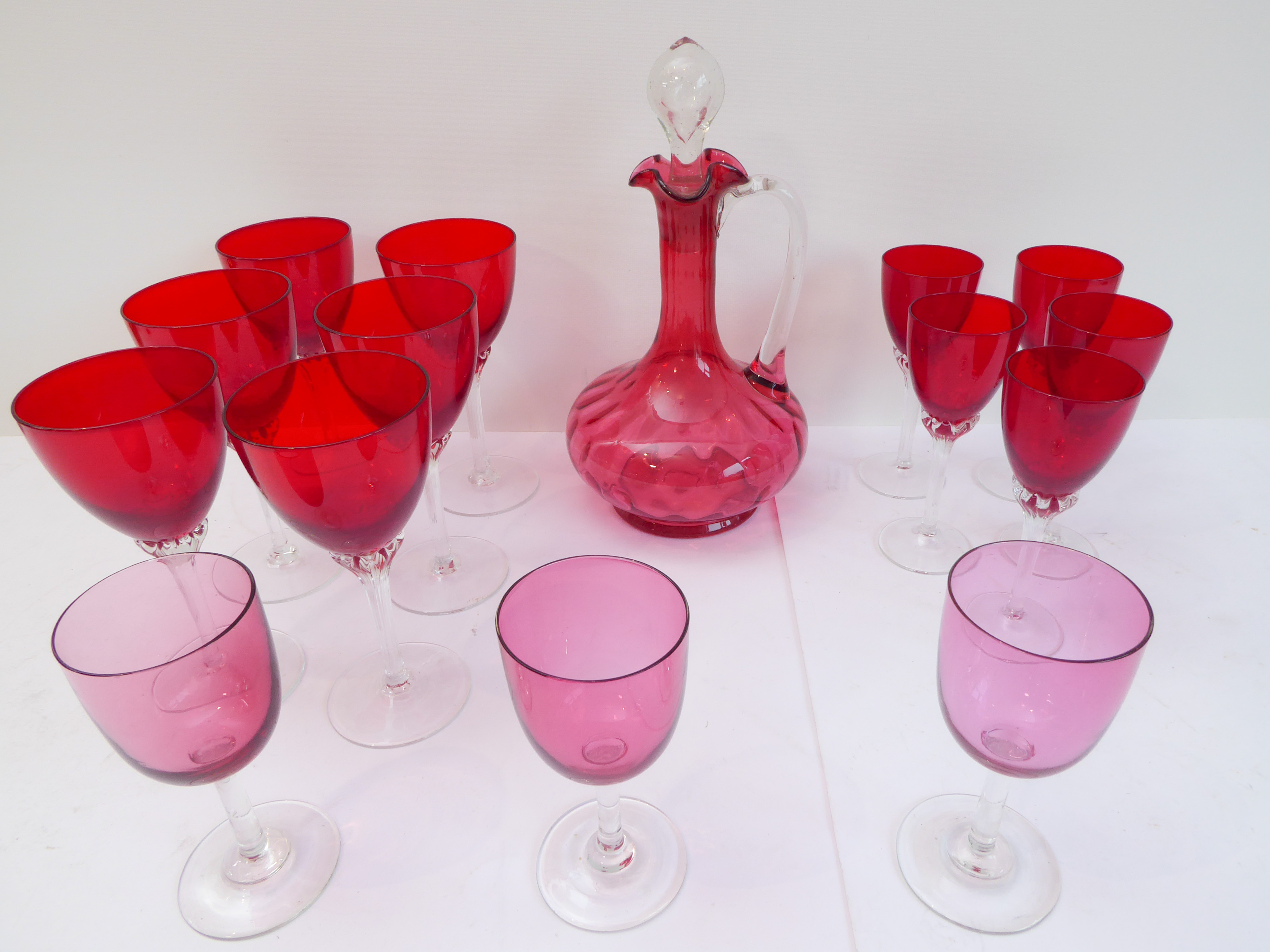 A 19th century cranberry glass globe-and-shaft style decanter, together with a set of six wines, a