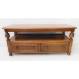 An Ercol elm side unit: the thumbnail moulded top above two arcaded half-width drawers and raised on