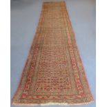 A 20th century Turkish hand-woven runner with red ground, geometric decoration and borders, wear