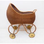An unusual 1920s boat-shaped wickerwork pram with scrolling supports and original painted wheels (