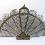 A 20th century brass fan-shaped folding fire-screen with ornate cast shell and scroll decoration (