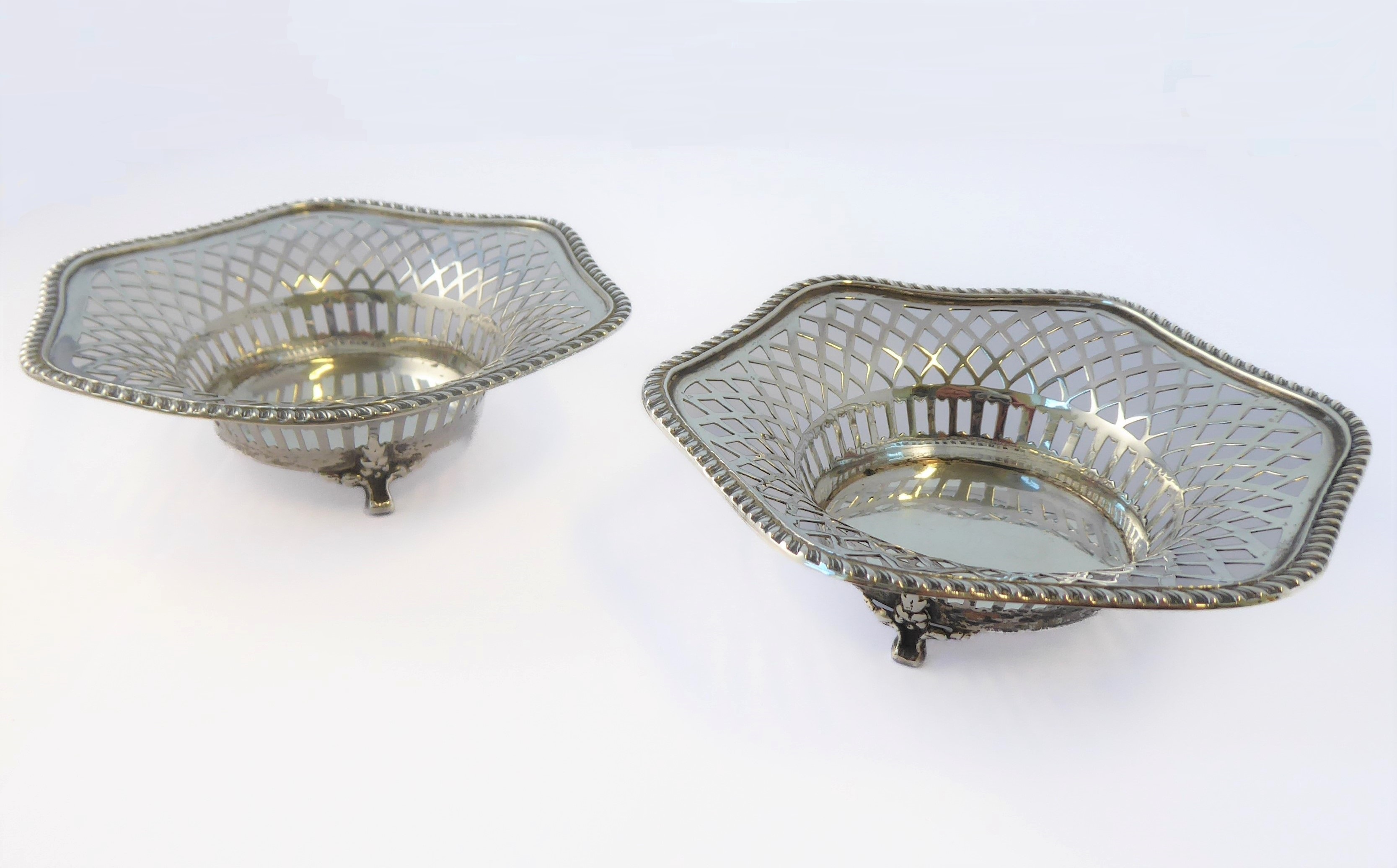 A pair of pierced hallmarked silver bonbon dishes of hexagonal form and on three legs, assayed