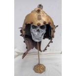 ARTS AND CRAFTS MALAYSIAN STYLE HELMET ON A COMPOSITE HUMAN SKULL STAND