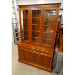 NATHAN YEW WOOD BOOKCASE WITH 3 GLASS PANEL DOORS AND GLASS SHELVED INTERIOR OVER BASE OF 3 DRAWERS