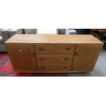 ERCOL BLONDE BEECH SIDEBOARD OF 3 CENTRAL DRAWERS FLANKED BY 2 PANEL DOORS,