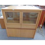MODERN OAK CABINET WITH GLASS SHELVES BEHIND 2 GLAZED PANEL DOORS OVER 2 DRAWERS AND 2 PANEL DOORS.