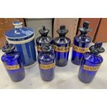 6 BLUE GLASS CHEMIST BOTTLES AND A WHITE AND BLUE PORCELAIN CHEMISTS JAR - 7 Condition