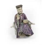 A Chinese Porcelain Figure of a Dignitary, Qianlong, sitting wearing purple robes, a scroll in his