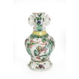 A Chinese Porcelain Vase, Kangxi, of fluted oval baluster form with twin scroll handles, painted