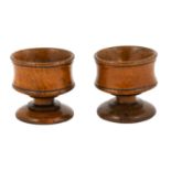 A Pair of Turned Treen Salts, early 19th century, the waisted cylindrical bowls on similar stems and