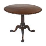 A George III-Style Carved Mahogany Tripod Table, the later circular flip-top on a fluted and