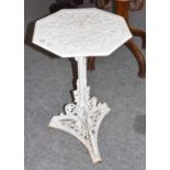 ~ A Victorian white painted cast iron garden table, on a triform scrolling support and with an