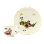 A Ludwigsburg Porcelain Teacup and Saucer, circa 1760, painted with landscape vignettes and scrolls,