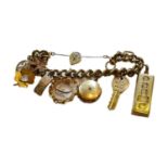A curb link bracelet, stamped ‘375’, hung with ten charms including an ingot, a key, a locket, a