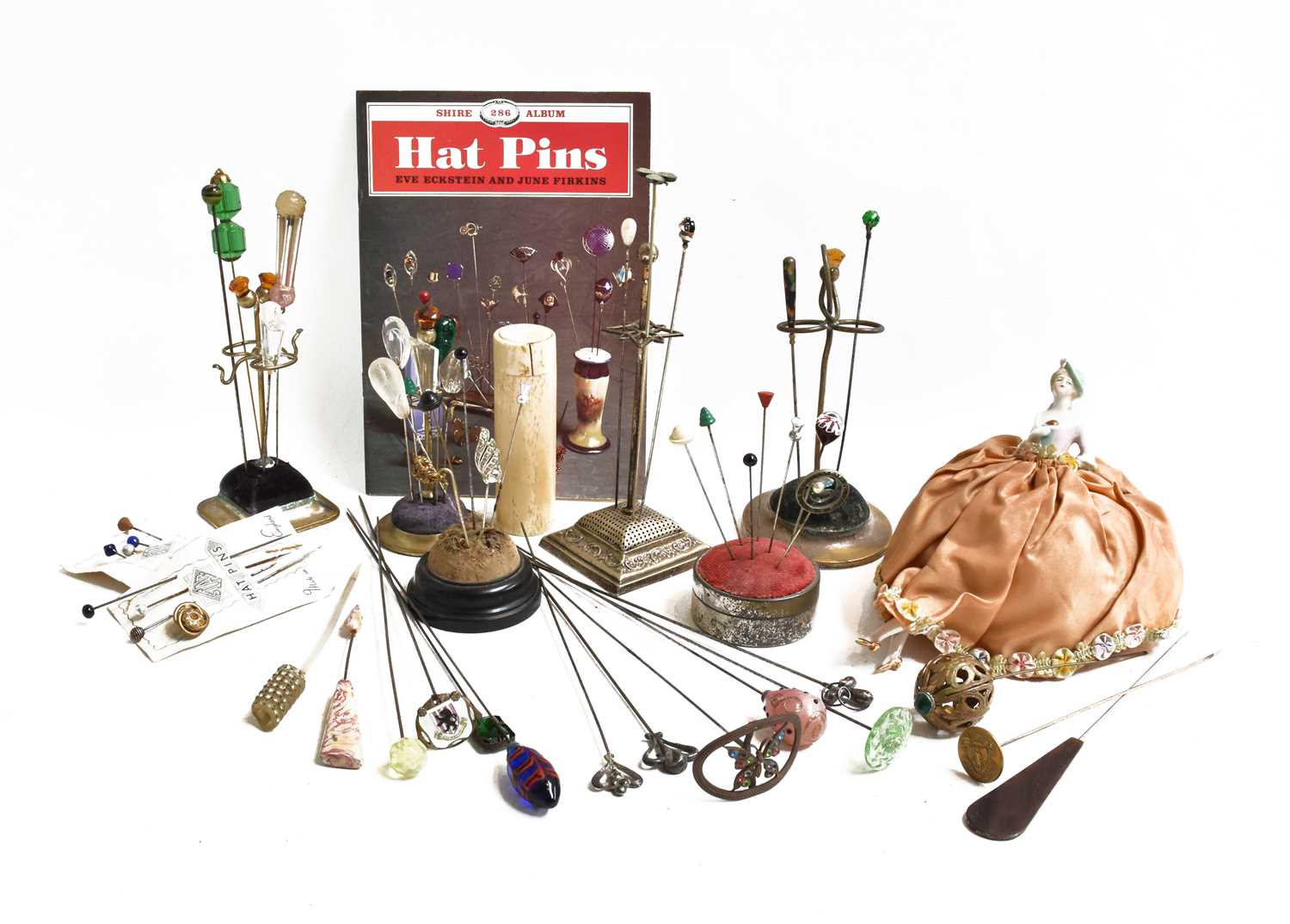 A collection of hatpins including four plated hat pin stands, one volume Shires Hat Pins, china half