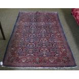 An unusual Kashan rug, the idnigo field with urns issuing flowers enclosed by madder flroal borders,